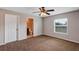 Bedroom featuring ceiling fan, window for natural light, door to bathroom and brown carpet at 16121 Sw 24Th Court Rd, Ocala, FL 34473