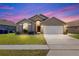 Charming single-story home with a well-manicured lawn, attached garage, and inviting front entrance during dusk at 2422 Black Powder Ln, Kissimmee, FL 34743