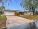 Street view of a one-story home showcasing a large driveway, attached garage, and lovely front yard at 2805 Grassmere Ln, Orlando, FL 32808