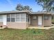 Charming exterior featuring a neutral-toned brick, a sunroom with large windows, and well-maintained landscaping at 2805 Grassmere Ln, Orlando, FL 32808