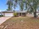 Charming one-story home featuring a well-manicured front yard with a large mature tree and attached two car garage at 2805 Grassmere Ln, Orlando, FL 32808