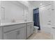 Well-lit bathroom featuring a double vanity with grey cabinets, a large mirror, and a shower with a blue curtain at 2977 Howley Aly, St Cloud, FL 34771