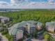 Wide aerial shot of Caribe Cove condos featuring lush greenery, parking, and distant lake views at 3050 Pirates Retreat Ct # 207, Kissimmee, FL 34747