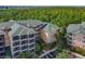 An aerial view of a multi-story condo building surrounded by lush greenery and ample parking at 3050 Pirates Retreat Ct # 207, Kissimmee, FL 34747