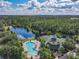 Beautiful aerial view of community pool, clubhouse, and tranquil lake surrounded by lush green trees at 3050 Pirates Retreat Ct # 207, Kissimmee, FL 34747