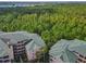 An aerial view of condo buildings surrounded by a dense forest, showcasing a tranquil setting at 3050 Pirates Retreat Ct # 207, Kissimmee, FL 34747