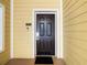 A dark front door with a black welcome mat, apartment number, and doorbell at 3050 Pirates Retreat Ct # 207, Kissimmee, FL 34747