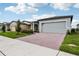 New home exterior showcasing a brick driveway, lush lawn, and 'Now Available' banner on the garage door at 3189 Viceroy Ct, Poinciana, FL 34759