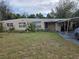 Exterior of a single-story home with a lawn, driveway, and partial carport in need of maintenance and repair at 39 N Oxalis Dr, Orlando, FL 32807