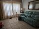 Living room with tile flooring, a light blue sofa, and a large window covered with curtains at 39 N Oxalis Dr, Orlando, FL 32807