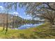 A scenic view of a lake surrounded by trees and green grass on a bright and sunny day at 4532 Saddleworth Cir, Orlando, FL 32826