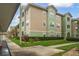 Exterior view of a modern condominium building with green and tan colors, surrounded by well-kept landscaping at 4865 Cypress Woods Dr # 2105, Orlando, FL 32811