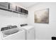 Efficient laundry room with front load washer/dryer, wire shelving, and neutral wall art at 6412 Tabebuia Pkwy, Winter Garden, FL 34787