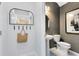 Stylish powder room features modern fixtures, textured wallpaper, and an arched mirror with coat hooks at 6412 Tabebuia Pkwy, Winter Garden, FL 34787