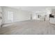 Open-concept living room featuring gray wood flooring, white walls, and a view into the kitchen at 6430 Sw 145Th Ln, Ocala, FL 34473