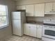 Well-lit kitchen featuring white cabinets, appliances, tile floors, and light countertops at 709 Michigan Ct # 4, St Cloud, FL 34769