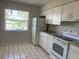 Bright kitchen with white appliances, white tile flooring, and grey countertops at 709 Michigan Ct # 4, St Cloud, FL 34769