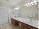 Bathroom featuring double sinks, tile flooring, white cabinets, walk-in shower and a large mirror at 1205 Bella Rose Ct, Davenport, FL 33896