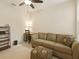 Cozy living room features a sofa, ottoman, desk, and shelving unit under a ceiling fan at 1205 Bella Rose Ct, Davenport, FL 33896