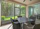 A screened porch with outdoor seating offers views of lush landscaping and sunlight at 1205 Bella Rose Ct, Davenport, FL 33896