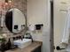 Stylish bathroom featuring a rectangular sink, brick accent wall with round mirror, and modern fixtures at 13413 Hopkinton Ct, Windermere, FL 34786