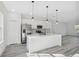A spacious white kitchen that includes an island, stainless steel appliances and stylish pendant lighting at 15163 Sw 29Th Terrace Rd, Ocala, FL 34473
