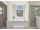 Bright bathroom featuring a soaking tub with a large window, and a glass-enclosed shower at 2398 Whitehorse St, Deltona, FL 32738