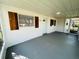 View of a covered porch with a blue door, wooden shutters, and a smooth gray floor surface at 2818 Geoffrey Dr, Orlando, FL 32826