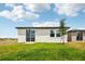 Back exterior view featuring sliding glass door, windows, and green lawn at 4002 Copperleaf Ln, Poinciana, FL 34759
