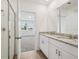 Bathroom featuring a glass shower, dual sinks with granite countertop, and view to bedroom at 4002 Copperleaf Ln, Poinciana, FL 34759