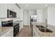 Modern kitchen features white cabinets, granite countertops, stainless steel appliances, and a center island with a sink at 4002 Copperleaf Ln, Poinciana, FL 34759