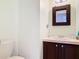 Cozy bathroom with dark wood vanity, cream countertop, decorative mirror, and white toilet at 554 Queensbridge Dr, Lake Mary, FL 32746