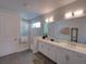 Modern bathroom featuring a double vanity, large mirror, and a luxurious glass-enclosed shower at 7464 Gathering Dr, Reunion, FL 34747