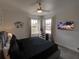 Modern bedroom with dark gray bed, flat screen TV, and two windows with natural light at 7464 Gathering Dr, Reunion, FL 34747