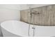 Close up of modern bathtub with chrome shower fixture and wood-look tile wall at 8015 Sw 133Rd Ln, Ocala, FL 34473