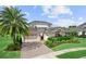 Beautiful home featuring a manicured lawn, mature palm tree, and a brick driveway leading to a spacious garage at 8614 Hata St, Orlando, FL 32827