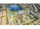 An aerial view showcases the community with a pool, tennis courts, and other amenities all centered around a lake at 8879 Geneve Ct, Kissimmee, FL 34747