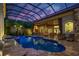 Twilight view of the enclosed pool area with an outdoor kitchen, bar, and lush foliage around the screened enclosure at 9212 Island Lake Ct, Orlando, FL 32836