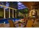 Beautifully lit pool area with an outdoor kitchen, fire pit, and lush greenery under a screened enclosure at 9212 Island Lake Ct, Orlando, FL 32836