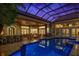 Gorgeous indoor pool with a glass roof, bar, and sitting area perfect for entertaining or relaxing at 9212 Island Lake Ct, Orlando, FL 32836