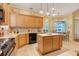 Kitchen featuring honey colored cabinets, tile backsplash, an island, and dining area at 10819 Woodchase Circle, Orlando, FL 32836