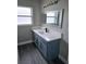 Modern bathroom with blue vanity, white countertop, and decorative mirror at 11500 Brandiwine Ct, Clermont, FL 34711