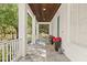 Inviting front porch with stone tile flooring, white columns, wood ceiling, and charming decor at 11521 Camden Park Dr, Windermere, FL 34786