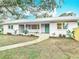 Charming single-story home featuring a metal roof, fresh landscaping, and inviting walkway to the turquoise front door at 1510 Live Oak St, New Smyrna Beach, FL 32168