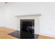 Close up view of a white fireplace with a decorative black tile surround in the corner of the living room at 1510 Live Oak St, New Smyrna Beach, FL 32168