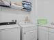 A laundry room with a sink, washer, dryer, shelves, and a green basket at 1511 Fairview Cir, Kissimmee, FL 34747