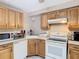 Bright kitchen featuring oak cabinets, white appliances, and tile flooring at 15523 Old Cheney Hwy, Orlando, FL 32828