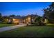 Dusk view of a beautiful home with a well-lit driveway, lush lawn, and a three-car garage at 1726 Brackenhurst Pl, Lake Mary, FL 32746