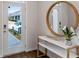 Bright foyer with a round mirror, white console table, and view of the outdoors through the front door at 2136 Monteverde Ave, Davenport, FL 33896