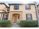 Charming two-story townhome featuring a welcoming arched doorway, shuttered windows and manicured front yard landscaping at 2511 Calabria Ave, Davenport, FL 33897